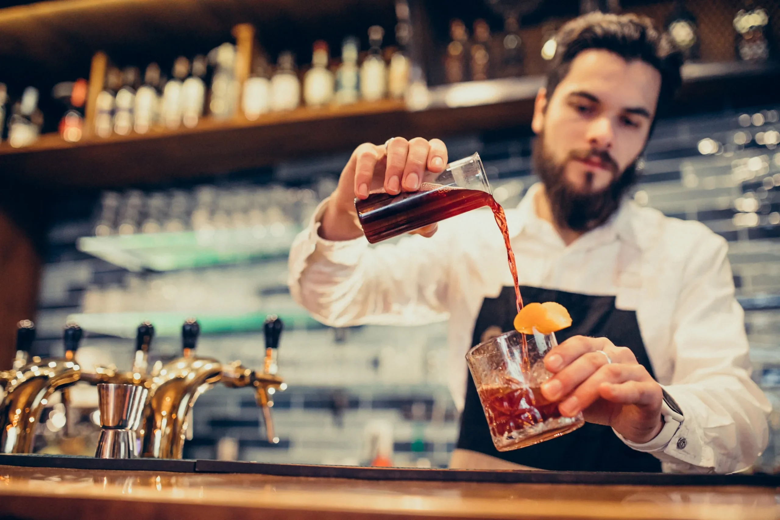 An bartender, who is considered a skilled laborer poors a cocktail