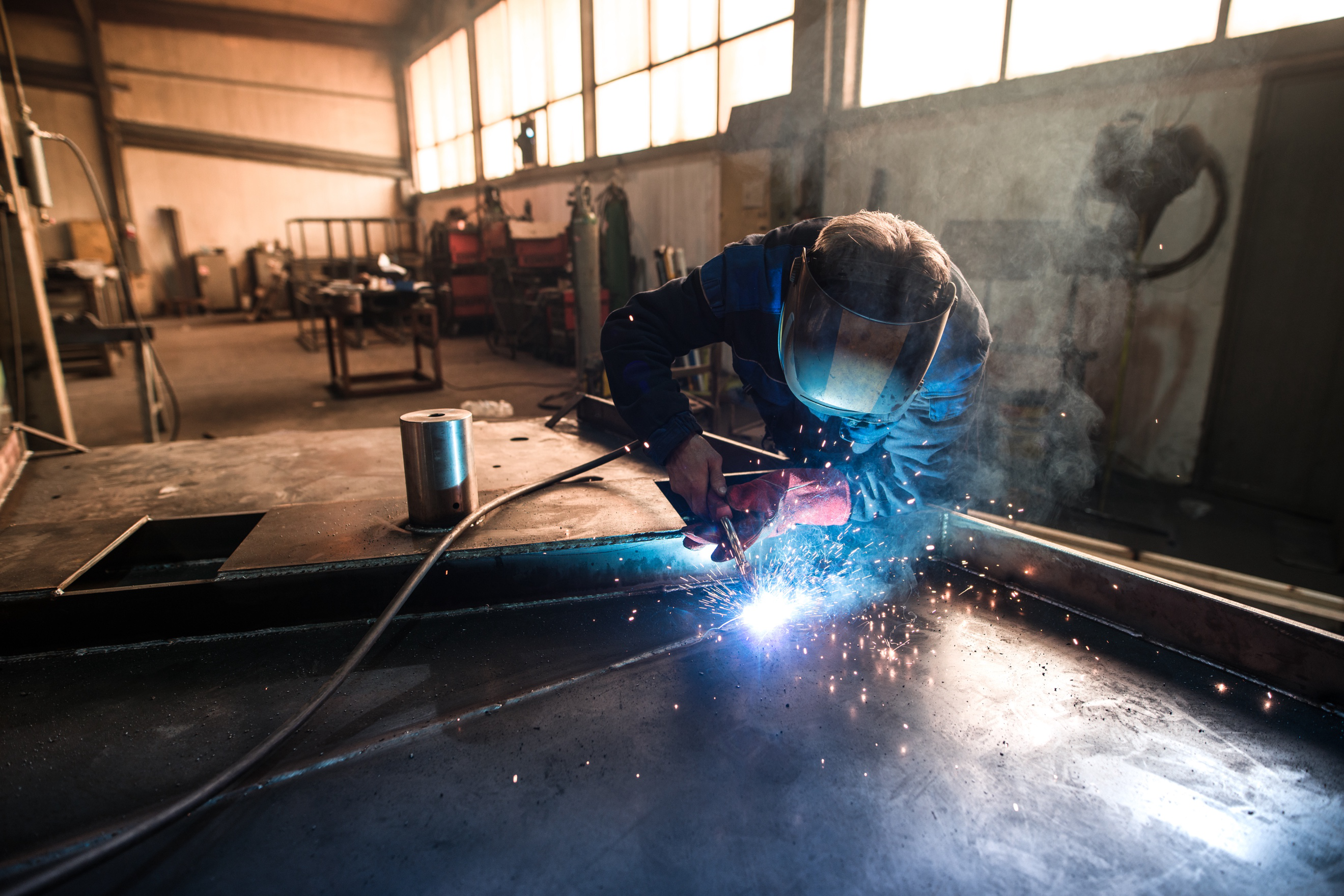 A skilled laborer welder welds a piece of metal