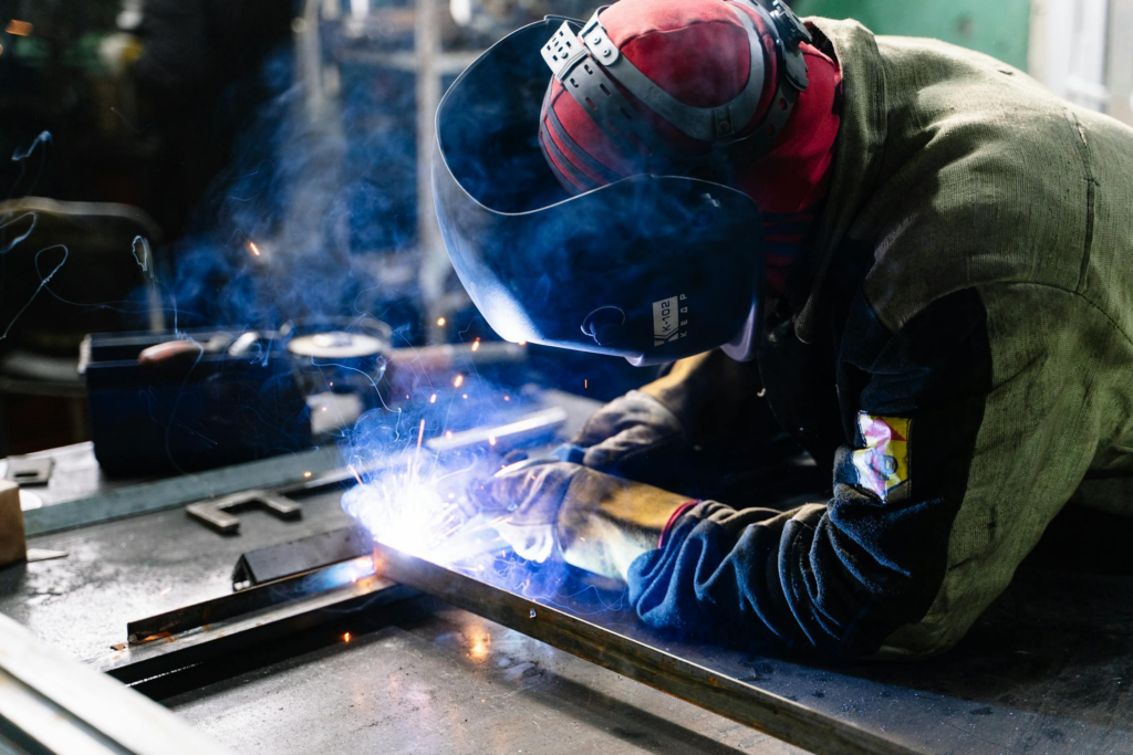 Temporary skilled laborer welding metal bars at a worksite while wearing PPE