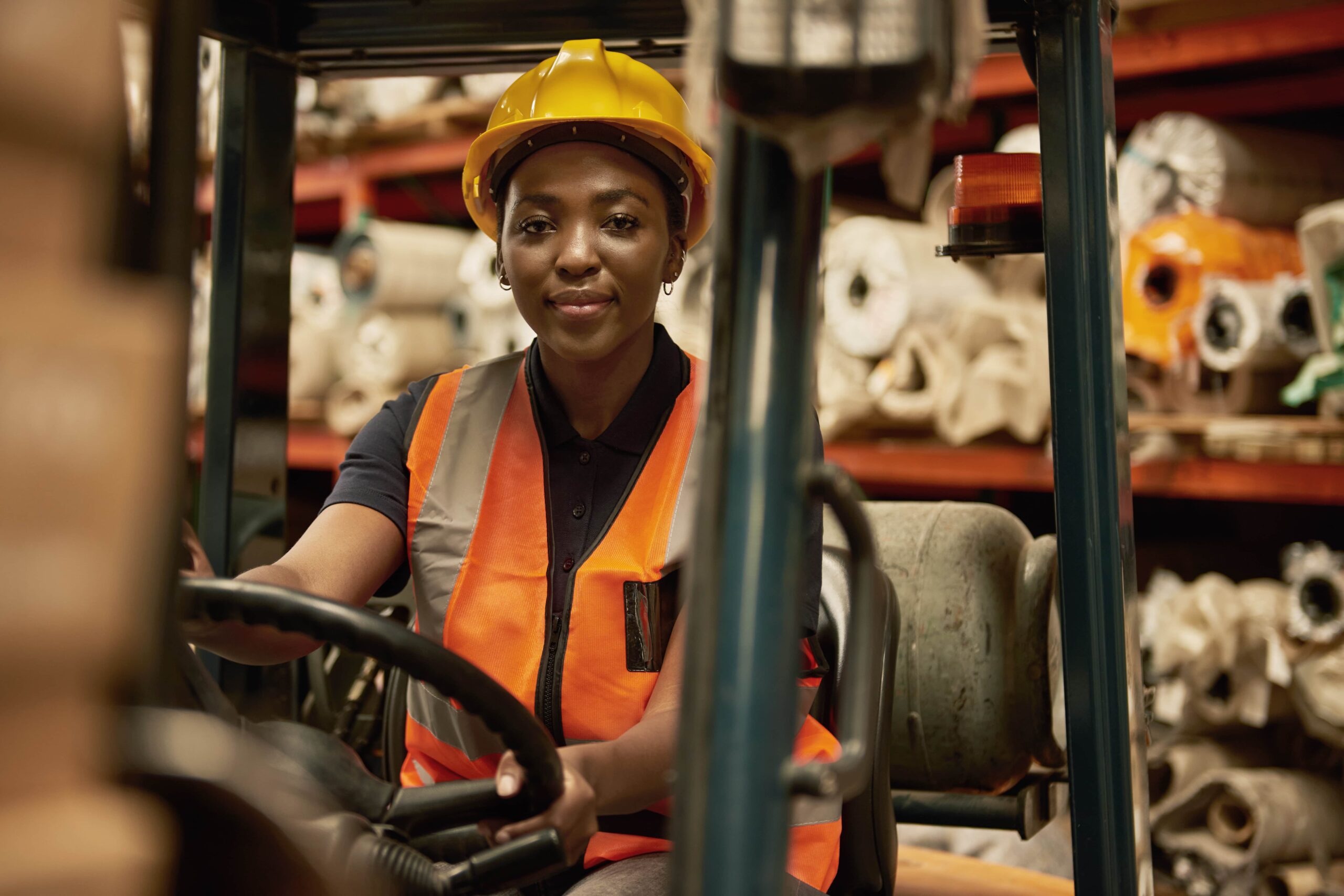 a skilled labor forklift driving in the cab in front of rolls of materials