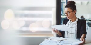 a woman sitting at a desk looks at papers as part of her payroll services duties