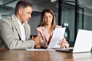 two payroll services professionals review documents as part of employee benefits duties