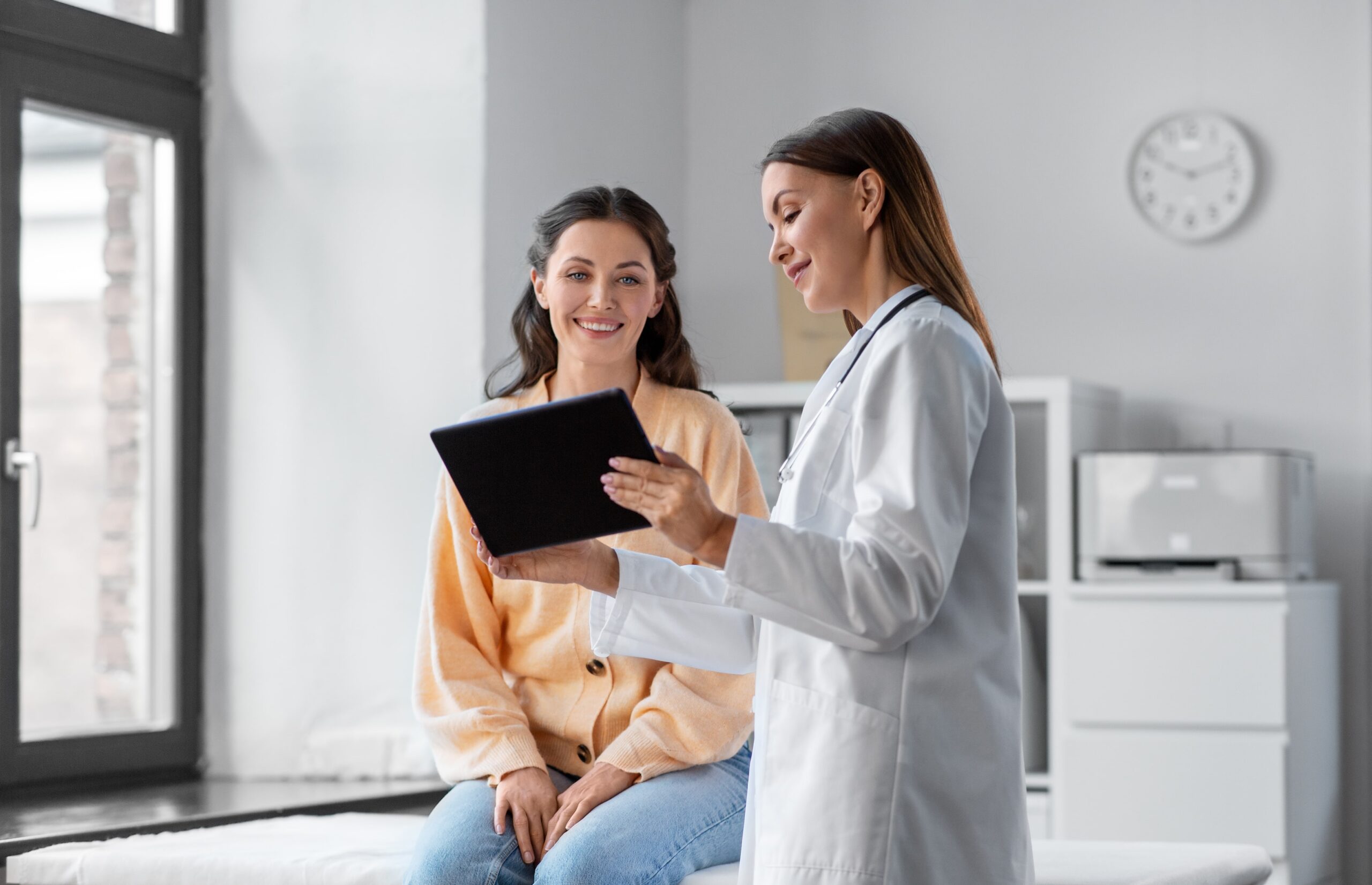 a woman sites on an examination table talking with her doctor