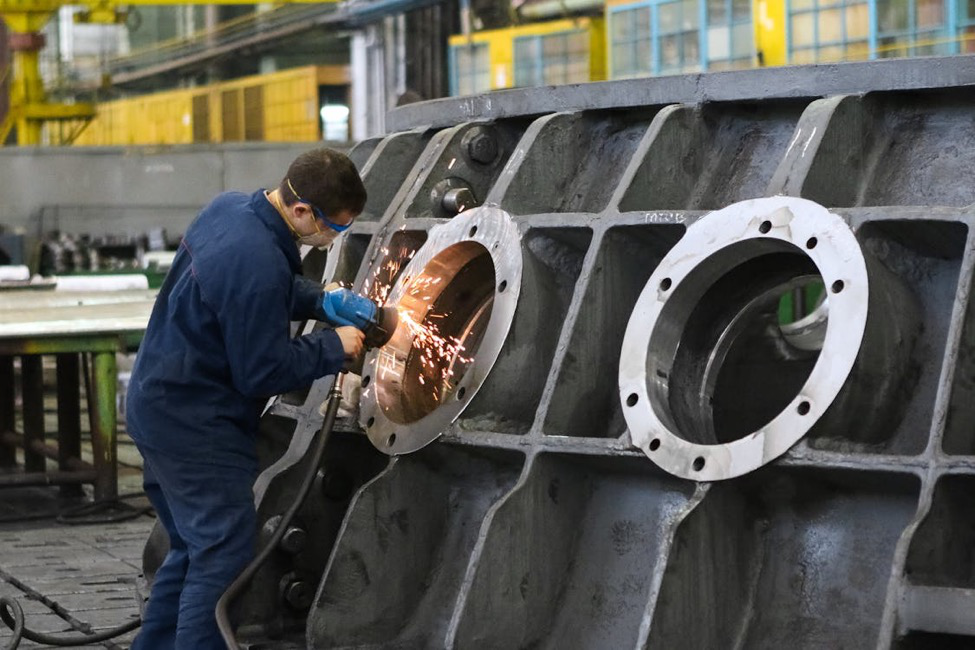 A man grinding metal around a metal structure