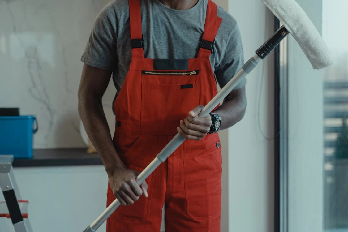 A person holding a wiper and wearing orange overalls