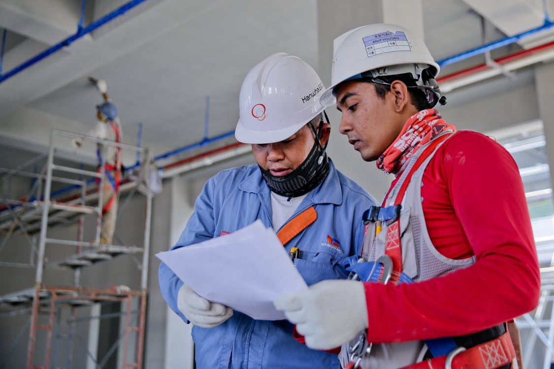 Two industrial laborers discussing paperwork at a facility