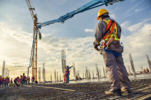 Construction worker wearing a hard hat and safety vest look up at a site.