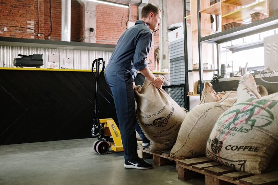 A man placing bags on wooden pallets