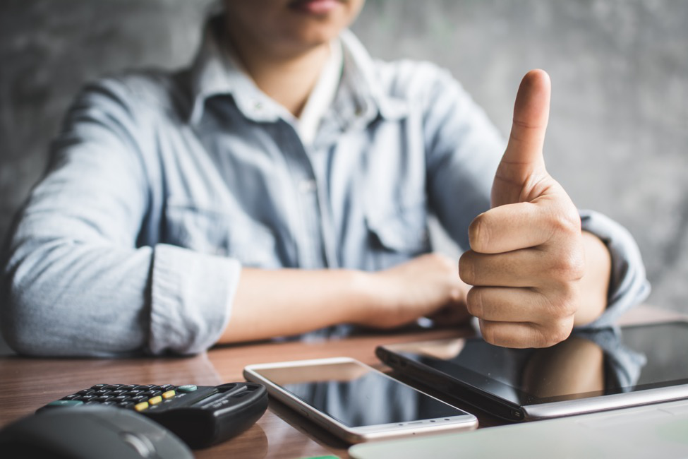 a worker gives the thumbs up after receiving notice on his mobile device that he’s been paid.