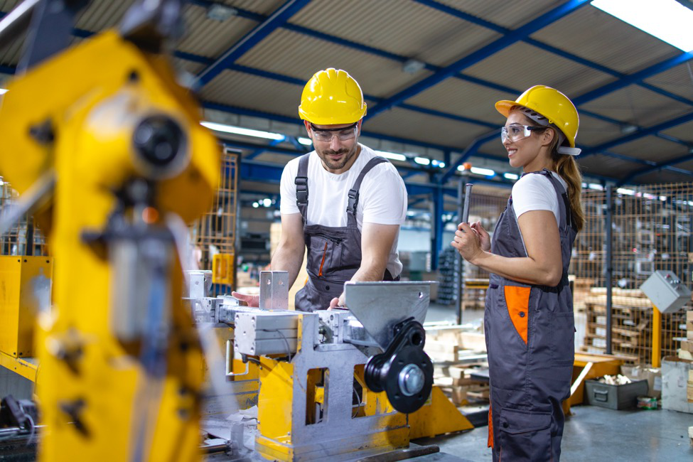 A man and a woman who are industrial workers in a manufacturing facility.