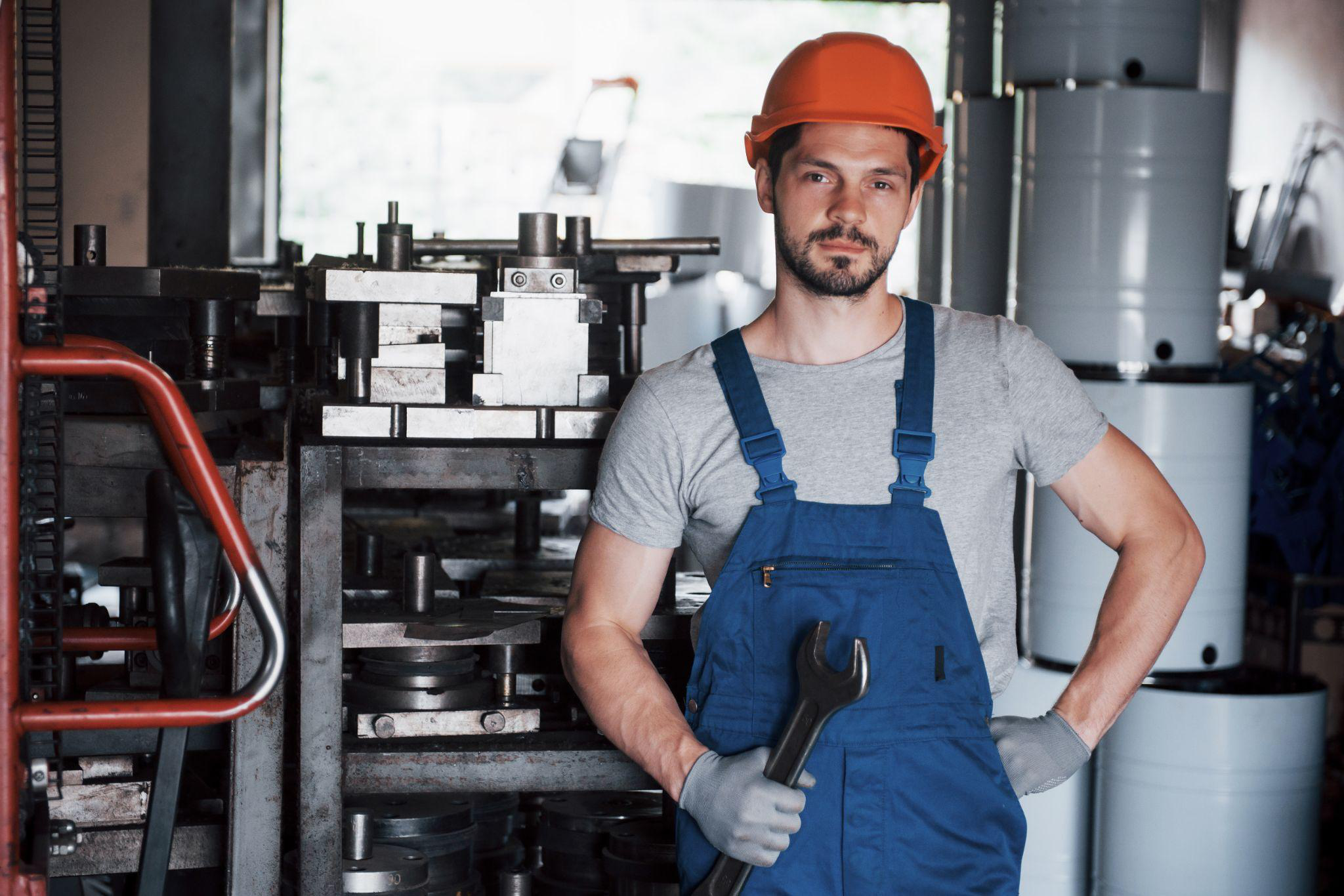 A person holding a manufacturing tool while wearing a helmet