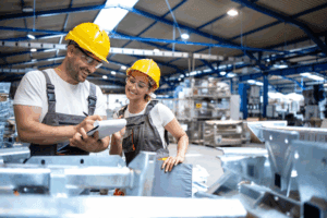 Two people in PPE looking at a clipboard and surrounded by cartons