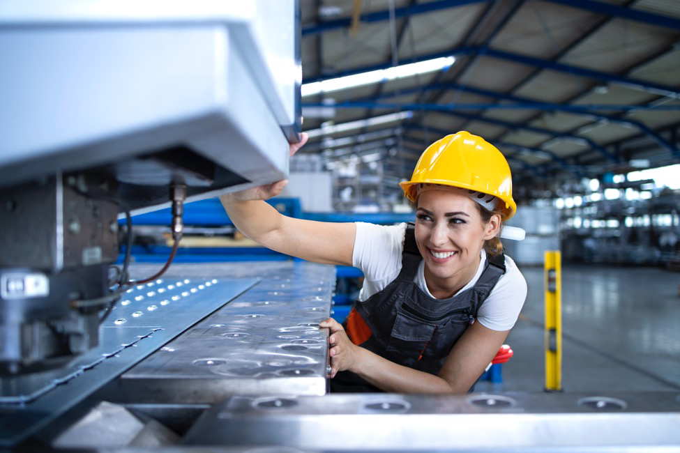 A woman in a yellow helmet using a machine