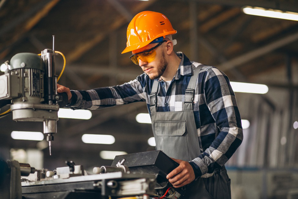 A skilled laborer in a safety hat using a machine