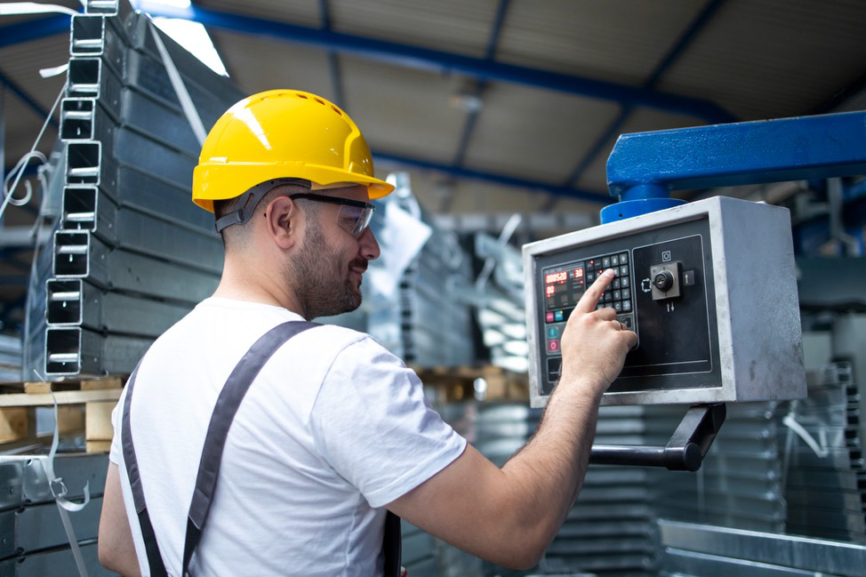 A person in a safety hat using an industrial machine