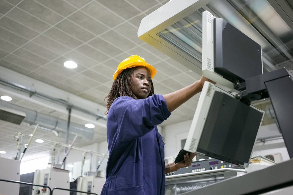 A person in a safety hat using an industrial machine