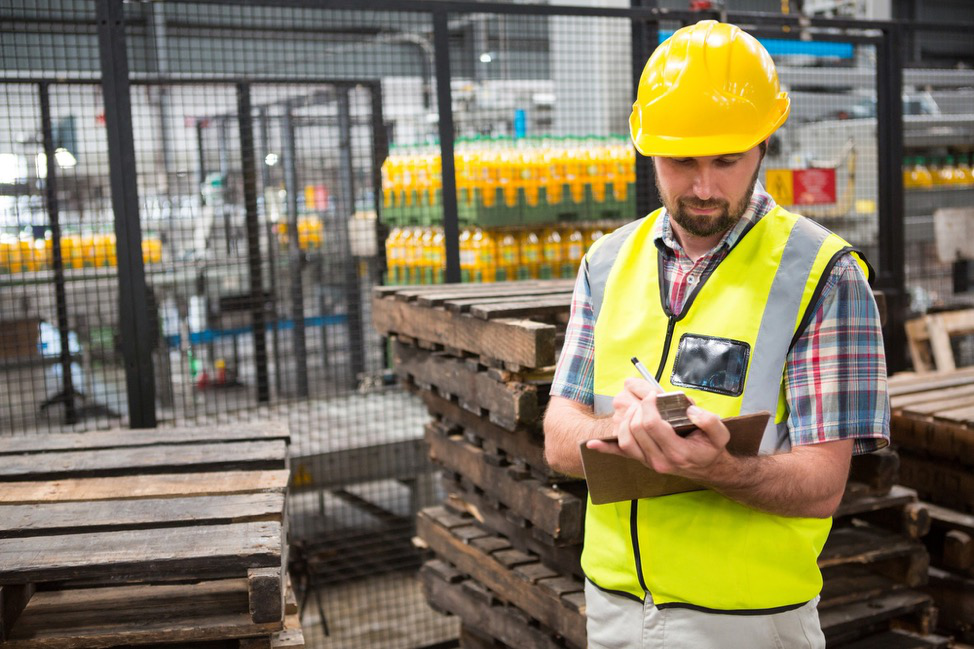 A person in PPE writing on a clipboard