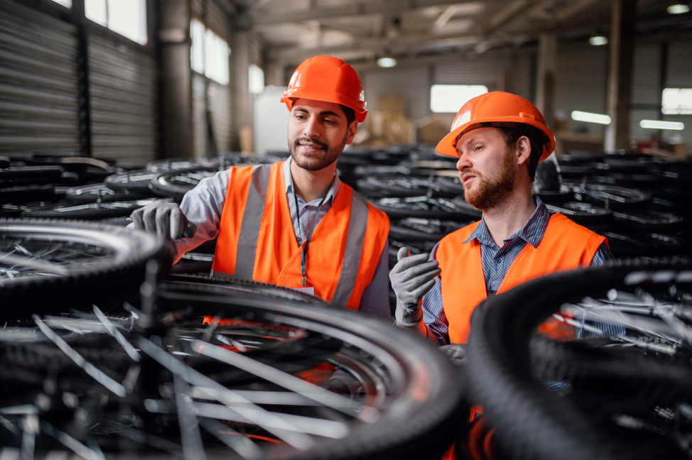 Two men in safety gear surrounded by bicycle wheels