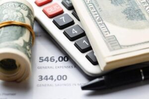 A calculator, money, and a pen placed on top of a paper