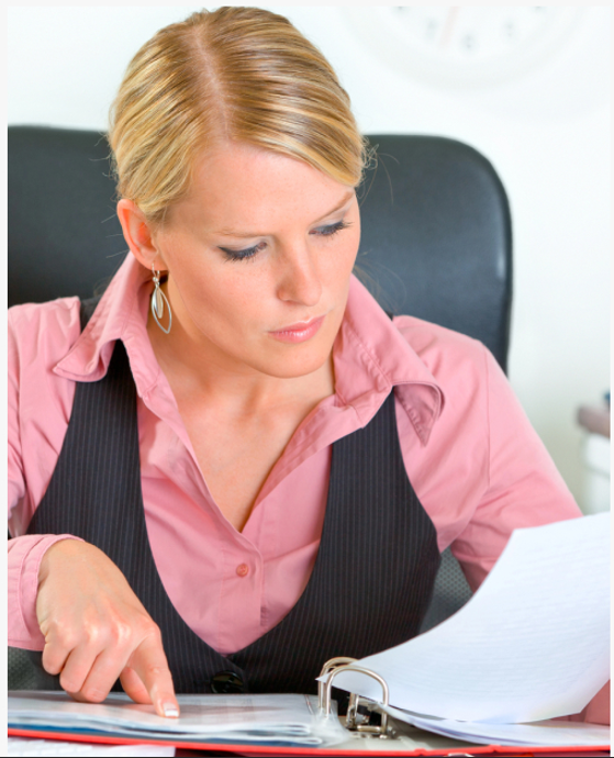 A professional woman focused on analyzing financial documents for payroll compliance and risk management.